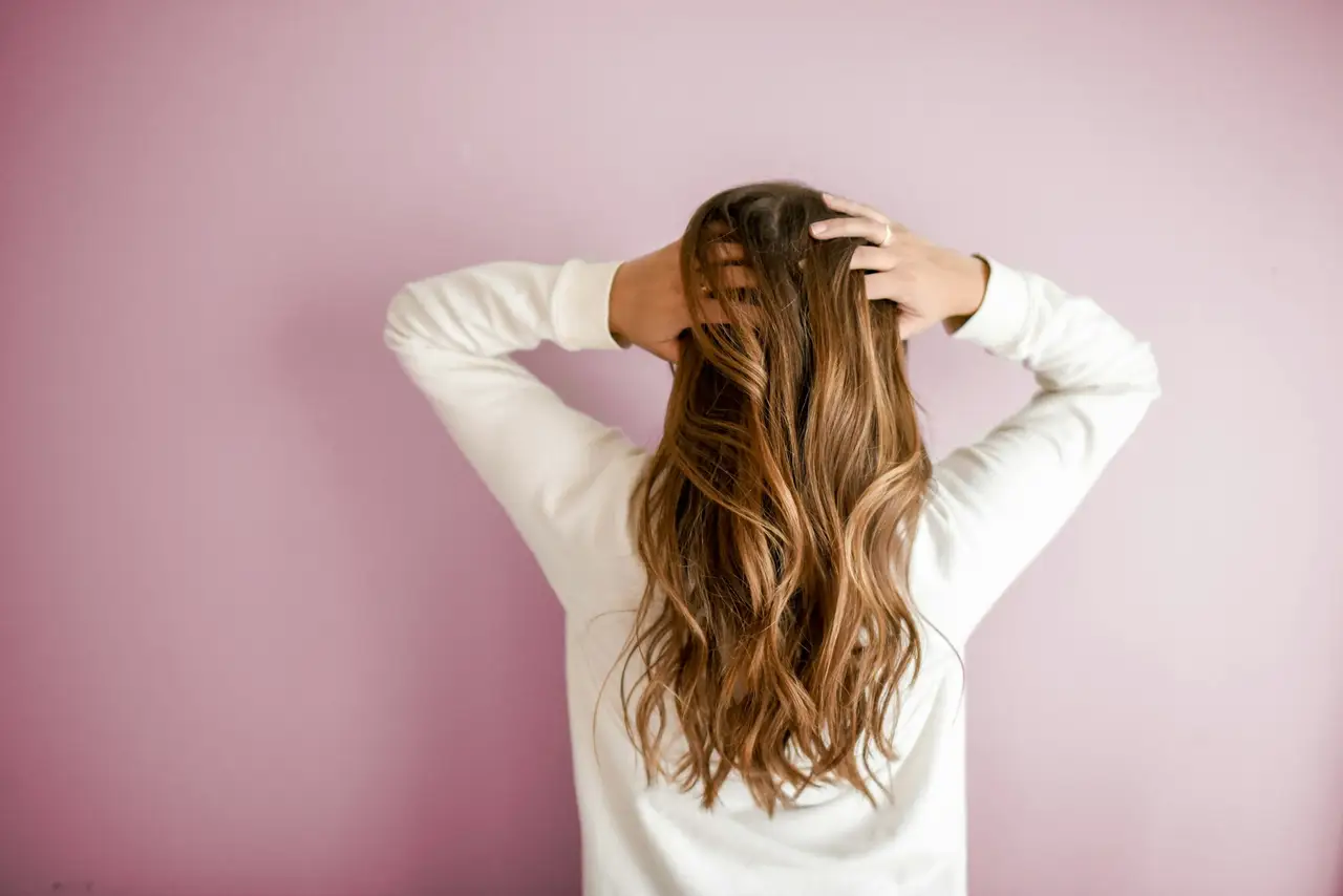 Femme aux cheveux longs, de dos, sur fond rose poudré